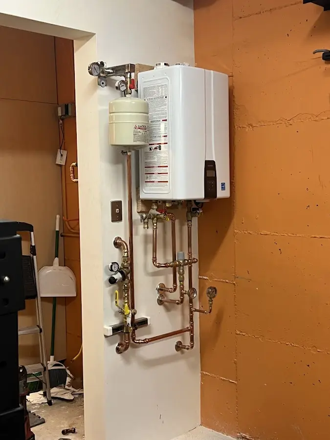 Plumbing technician inspecting water heater connections in West Allis